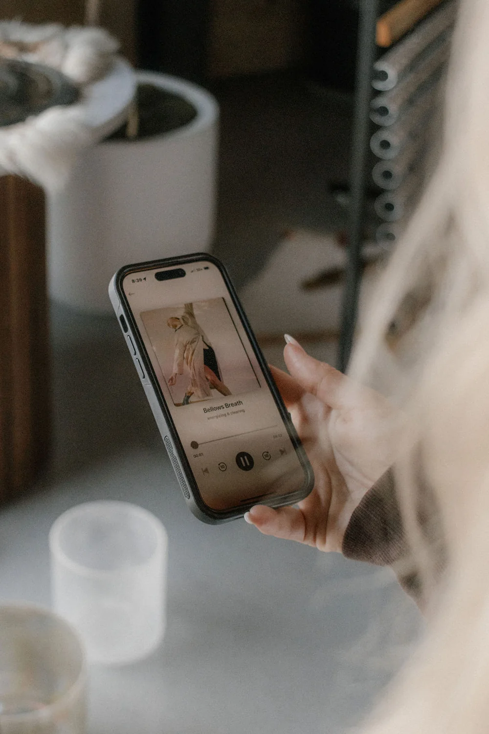 A woman holding her phone, playing Bellows Breath from the Déjà Well library