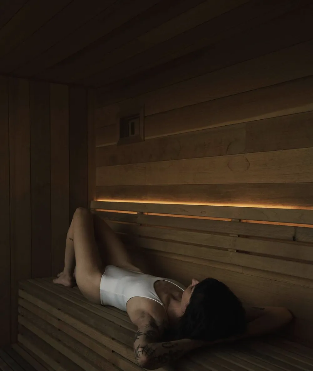 A woman resting on a cedar bench inside a sauna